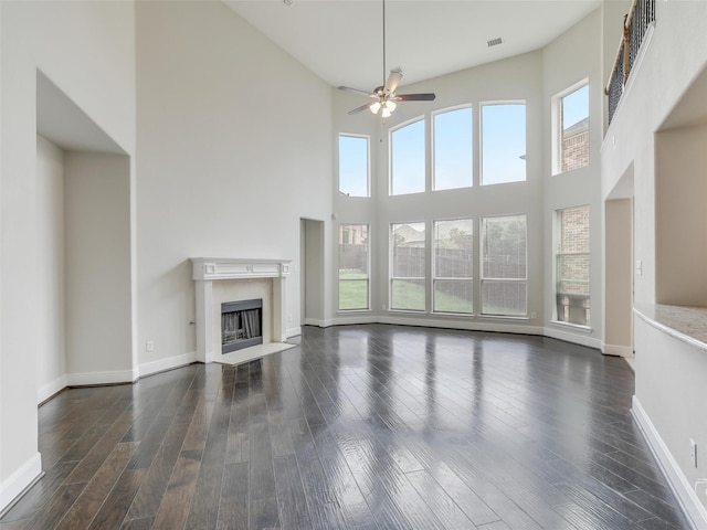 unfurnished living room with dark wood-style floors, a premium fireplace, and a wealth of natural light