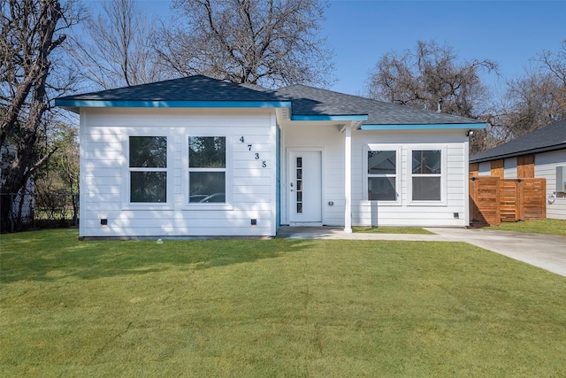 view of front of house featuring a shingled roof, fence, and a front yard