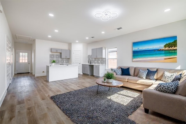 living room featuring recessed lighting, visible vents, attic access, light wood-type flooring, and baseboards