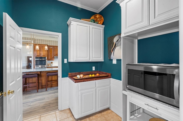 kitchen featuring crown molding, white cabinets, stainless steel appliances, and decorative light fixtures
