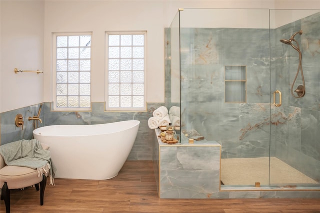bathroom featuring plenty of natural light, a stall shower, a soaking tub, and tile walls