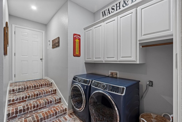 clothes washing area with baseboards, brick floor, cabinet space, and washer and dryer