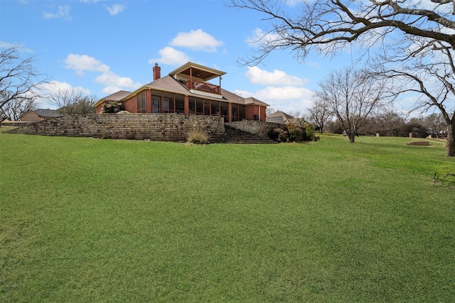 back of property featuring a sunroom, a lawn, and a chimney