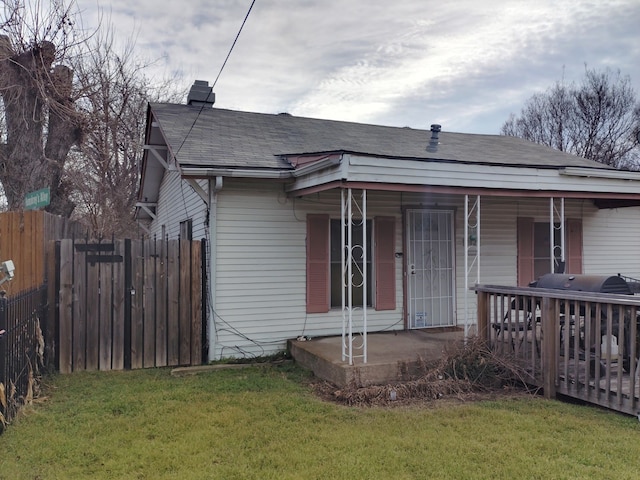 view of front of home with a shingled roof, a chimney, fence, and a front yard