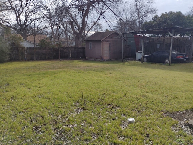 view of yard with a storage unit, fence, a carport, and an outbuilding