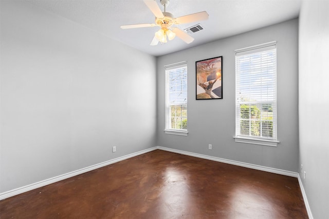 spare room with finished concrete flooring, a ceiling fan, visible vents, and baseboards