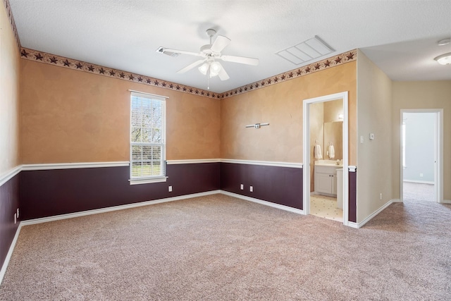 carpeted spare room with baseboards, a textured ceiling, visible vents, and a ceiling fan