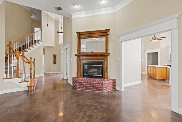 living area featuring a fireplace, visible vents, baseboards, ornamental molding, and dark wood-style floors