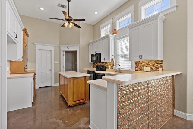 kitchen with light countertops, visible vents, decorative backsplash, a kitchen island, and black appliances