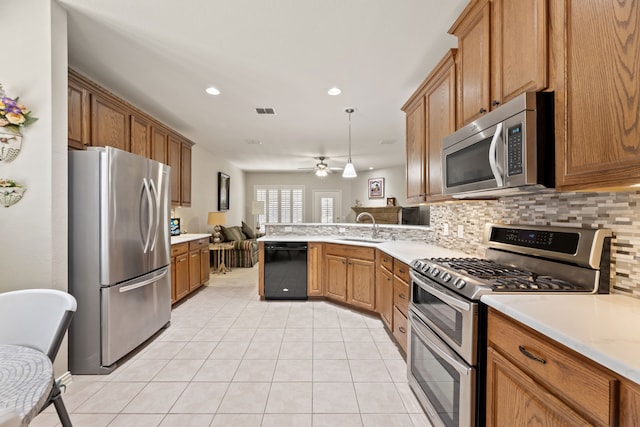 kitchen featuring tasteful backsplash, open floor plan, light countertops, stainless steel appliances, and a sink