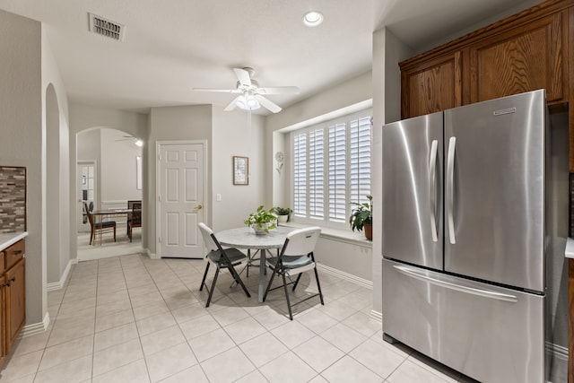 dining space featuring light tile patterned floors, ceiling fan, visible vents, and arched walkways