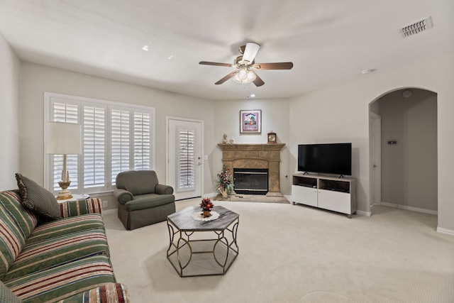 living room with arched walkways, carpet flooring, visible vents, baseboards, and a ceiling fan