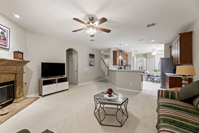 living room with arched walkways, a premium fireplace, visible vents, and light colored carpet