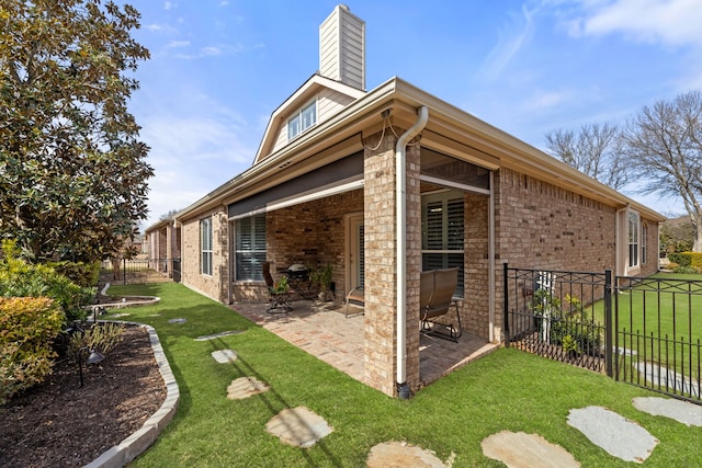 exterior space with brick siding, a chimney, fence, and a patio