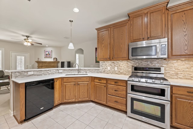 kitchen featuring a peninsula, a sink, open floor plan, light countertops, and appliances with stainless steel finishes