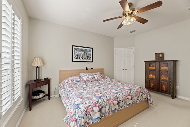 carpeted bedroom featuring ceiling fan, multiple windows, visible vents, and baseboards