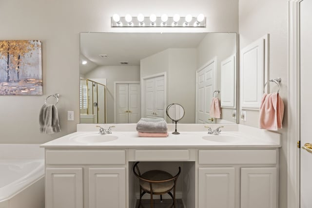 bathroom featuring a bath, a stall shower, double vanity, and a sink