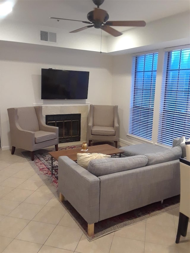 living room featuring visible vents, baseboards, a glass covered fireplace, ceiling fan, and tile patterned floors