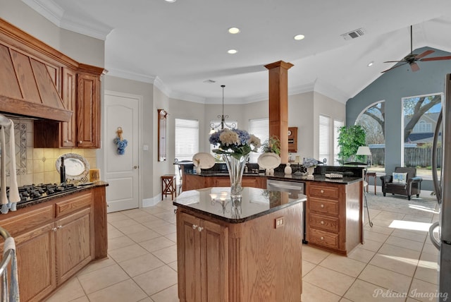 kitchen featuring light tile patterned floors, a peninsula, visible vents, a center island, and crown molding