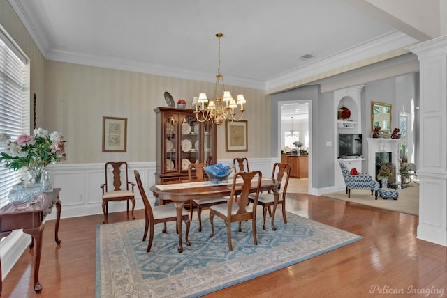 dining space with crown molding, a fireplace, a chandelier, and built in features