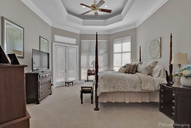 bedroom with light carpet, ceiling fan, a tray ceiling, and ornamental molding