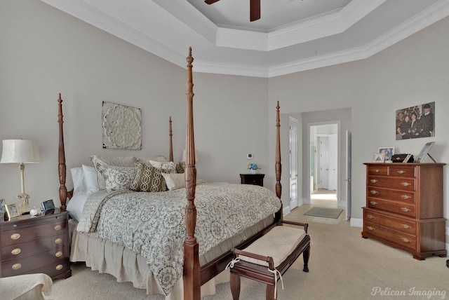 bedroom featuring ornamental molding, a tray ceiling, light carpet, and a ceiling fan