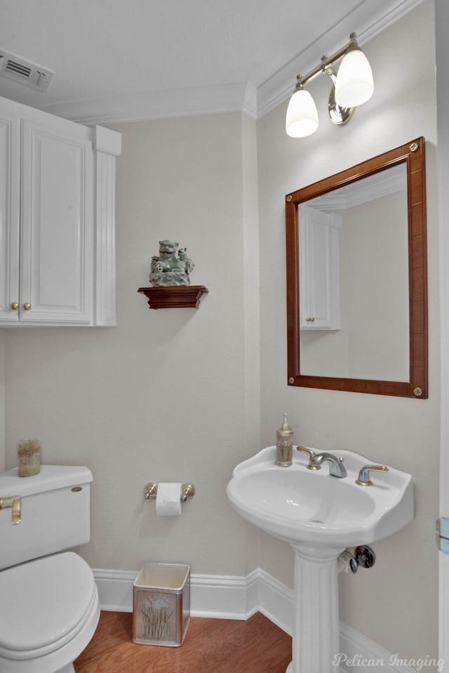 bathroom with visible vents, toilet, ornamental molding, wood finished floors, and baseboards