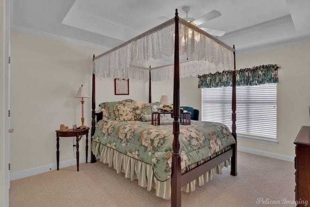 carpeted bedroom with ceiling fan, baseboards, a raised ceiling, and crown molding