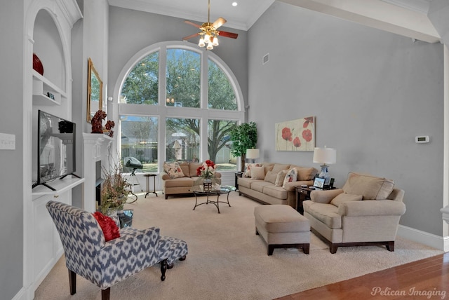 living room featuring a fireplace, visible vents, a towering ceiling, baseboards, and ornamental molding