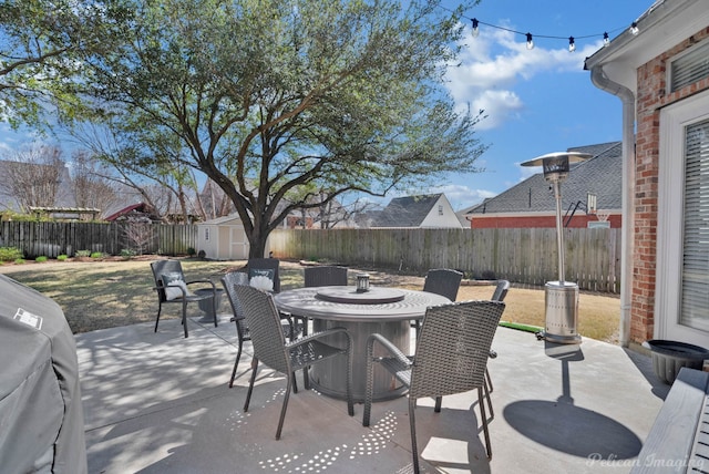 view of patio / terrace featuring a storage unit, outdoor dining space, an outbuilding, and a fenced backyard