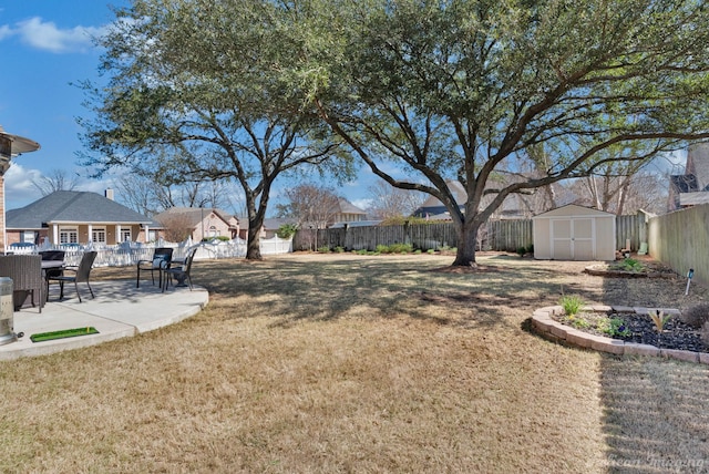 view of yard featuring a storage shed, a fenced backyard, a patio, and an outbuilding