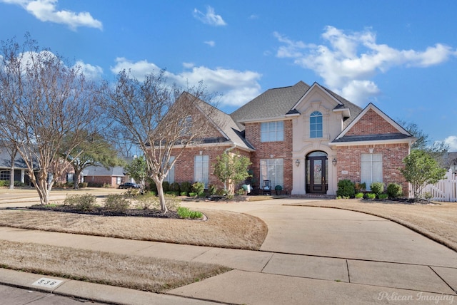 view of front of home with brick siding, driveway, and roof with shingles