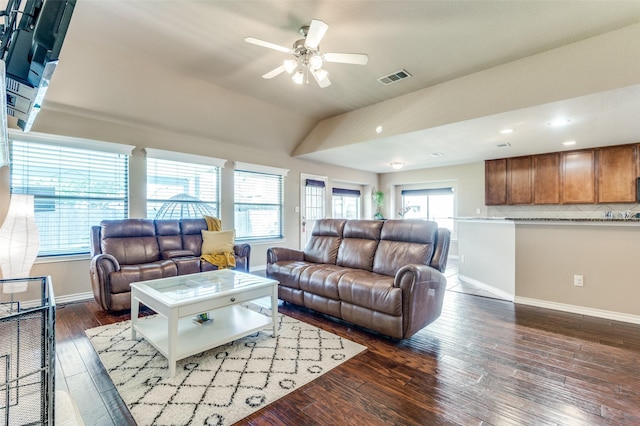 living area with a healthy amount of sunlight, visible vents, vaulted ceiling, and dark wood-type flooring