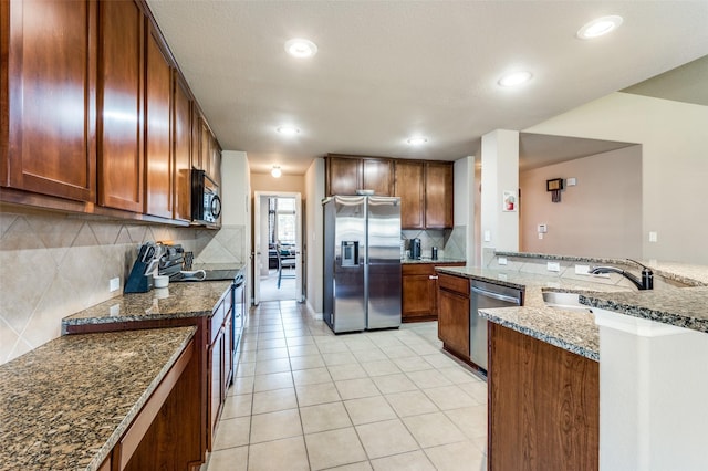 kitchen with light tile patterned floors, tasteful backsplash, dark stone counters, appliances with stainless steel finishes, and a sink