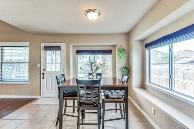 dining area with a wealth of natural light, light tile patterned flooring, and baseboards