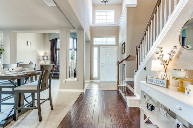 entryway with visible vents, baseboards, dark wood finished floors, a high ceiling, and stairs