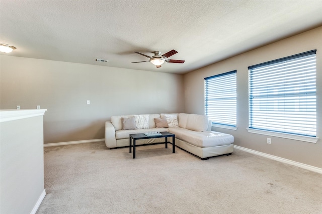 carpeted living area featuring a ceiling fan, visible vents, and baseboards