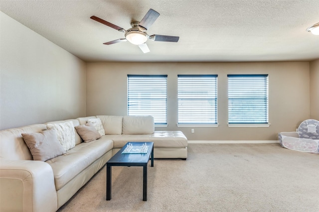 carpeted living room with ceiling fan, a textured ceiling, baseboards, and a healthy amount of sunlight