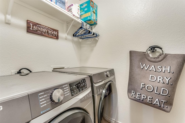 laundry room featuring a textured wall, laundry area, and washer and clothes dryer