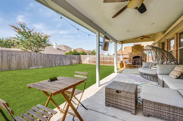 view of patio / terrace with an outdoor living space with a fireplace, a fenced backyard, and a ceiling fan