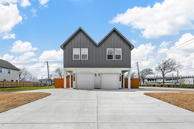 view of side of home featuring an attached garage, brick siding, fence, driveway, and board and batten siding