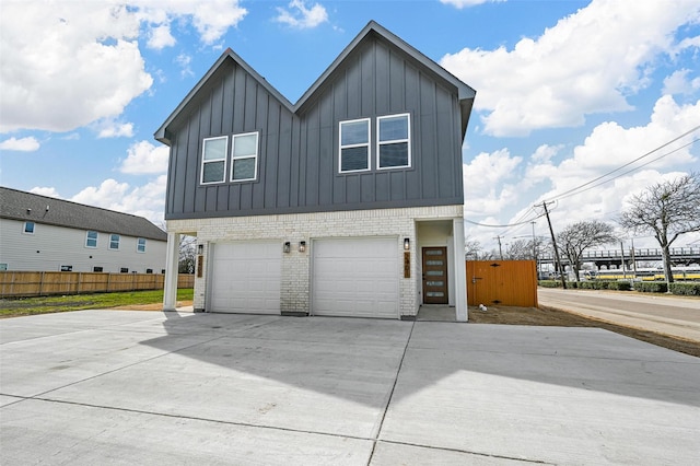 view of side of home with brick siding, concrete driveway, an attached garage, board and batten siding, and fence