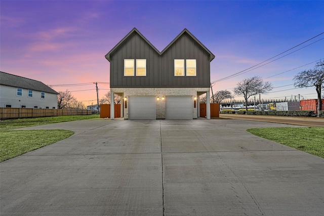 view of front facade with brick siding, an attached garage, board and batten siding, fence, and driveway