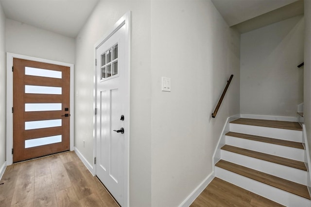 foyer entrance featuring stairs, baseboards, and wood finished floors