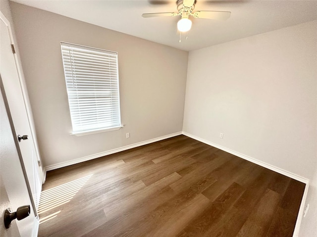 empty room featuring dark wood-type flooring, baseboards, and a ceiling fan