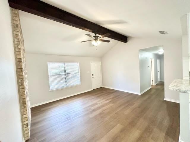 unfurnished room with lofted ceiling with beams, a ceiling fan, visible vents, baseboards, and dark wood-style floors