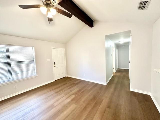 spare room featuring visible vents, vaulted ceiling with beams, baseboards, and wood finished floors