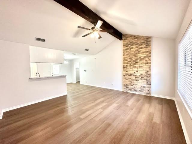 unfurnished living room featuring vaulted ceiling with beams, visible vents, ceiling fan, wood finished floors, and baseboards