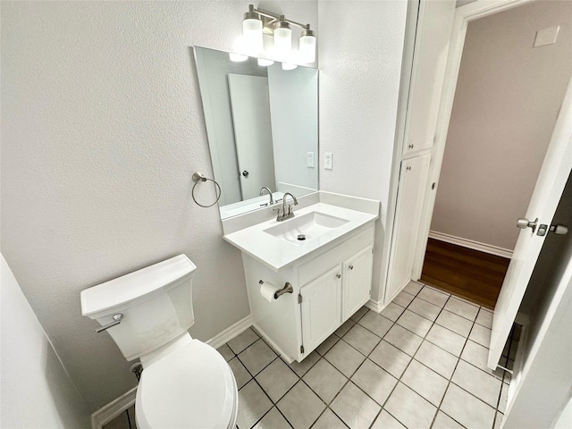 half bath featuring toilet, tile patterned flooring, baseboards, and vanity