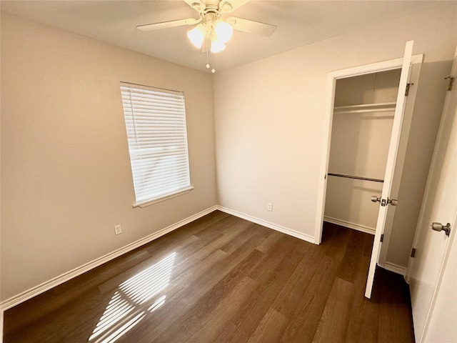 unfurnished bedroom with ceiling fan, a closet, baseboards, and dark wood-type flooring